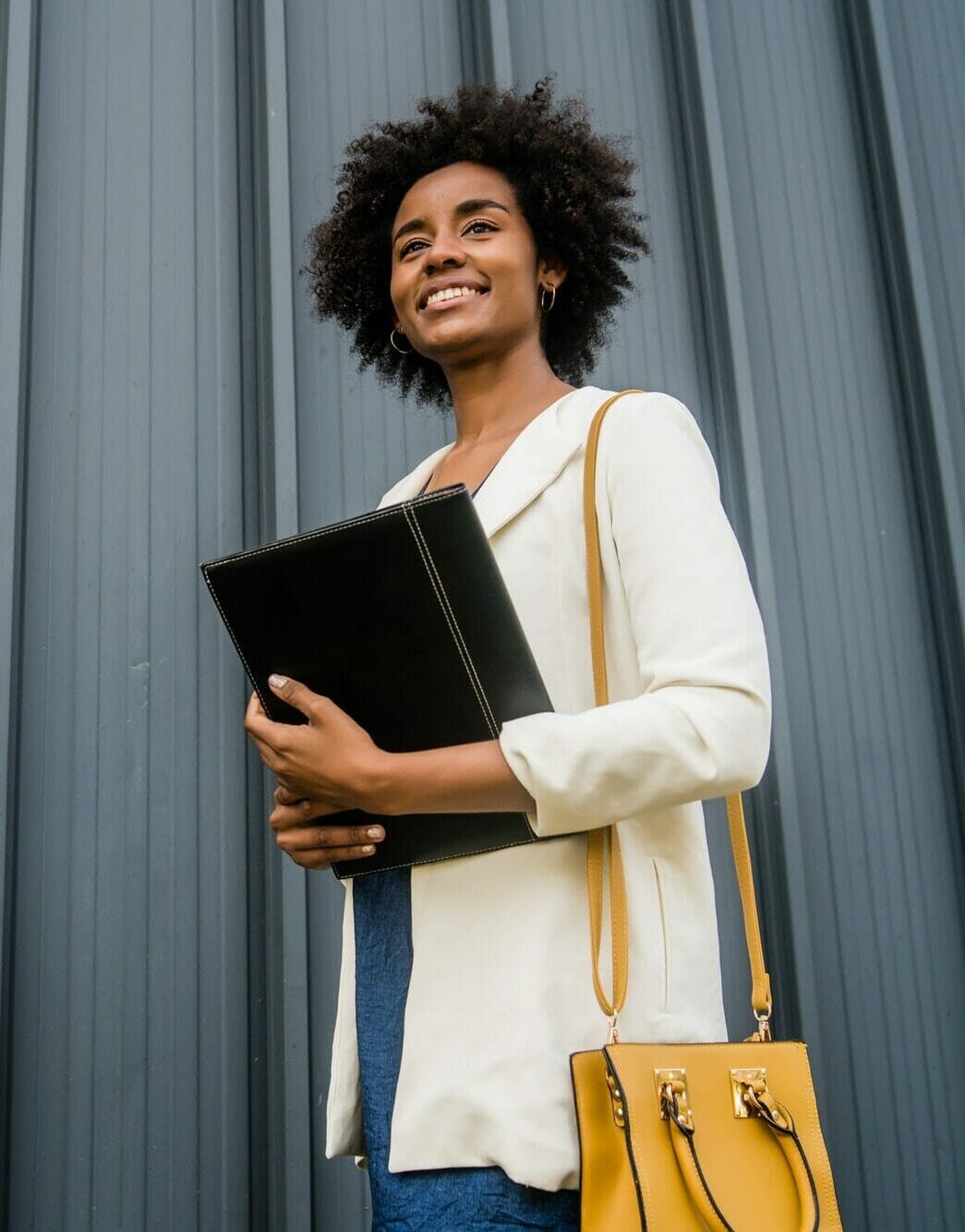 Afro businesswoman holding clipboard outdoors at the street.