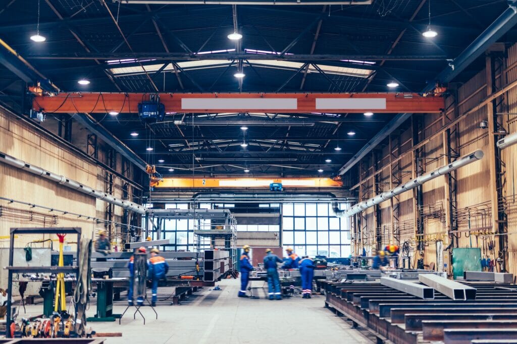 Large factory hall, blue-collar workers at work.